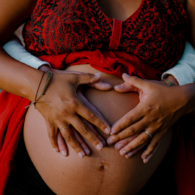 Close-up of four hands cradling a pregnant belly, symbolizing family connection, support, and generational love.
