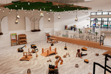 Large indoor sandbox at The Sand Garden in Issaquah with toy trucks, wooden bridges, and children playing.