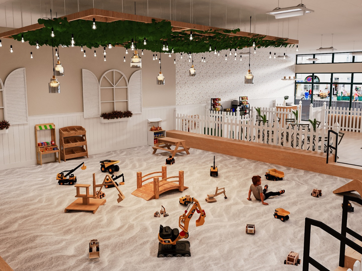 Large indoor sandbox at The Sand Garden in Issaquah with toy trucks, wooden bridges, and children playing.