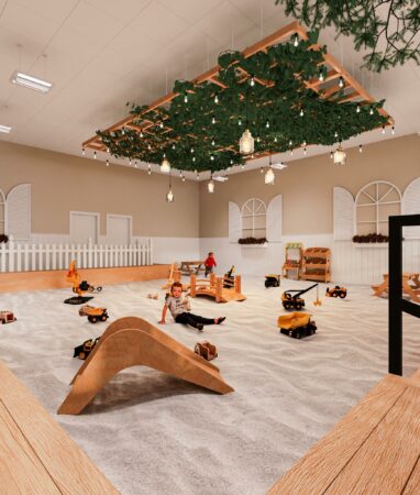 Large indoor sandbox at The Sand Garden in Issaquah with toy trucks, wooden bridges, and children playing.
