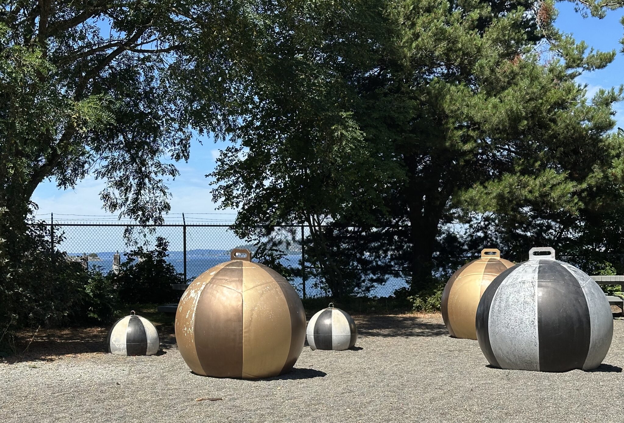 Sculpture of black, grey, and gold marine floats at Jack Block Park entrance