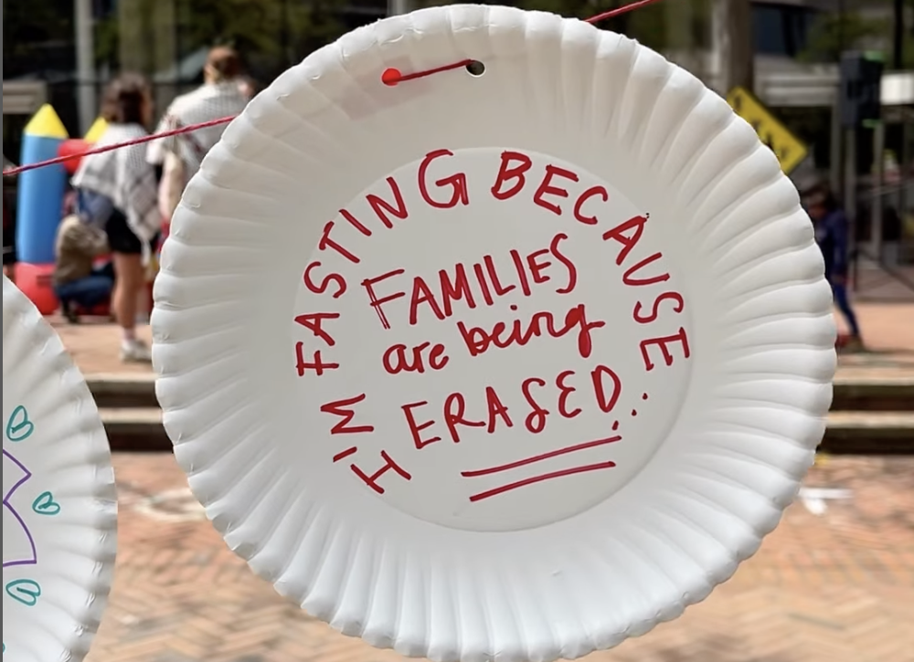 A paper plate with handwritten words: “I’m fasting because families are being erased.”