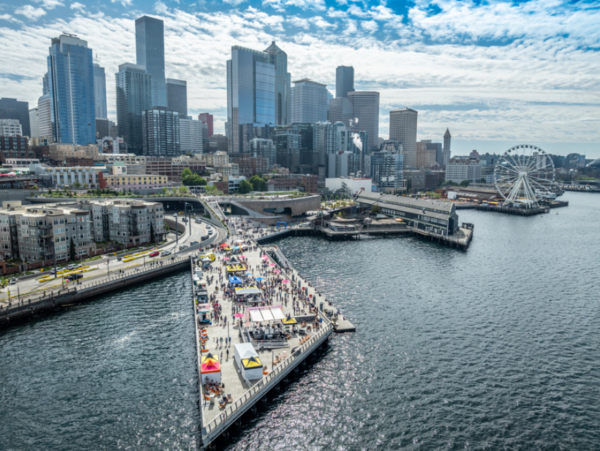 Aerial view of Seattle’s new 20-acre Waterfront Park filled with families enjoying the sunny grand opening celebration.