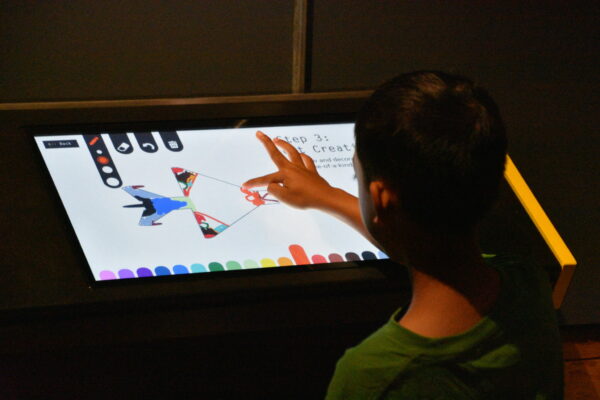 Young visitor engaging with digital art display at Museum of Flight