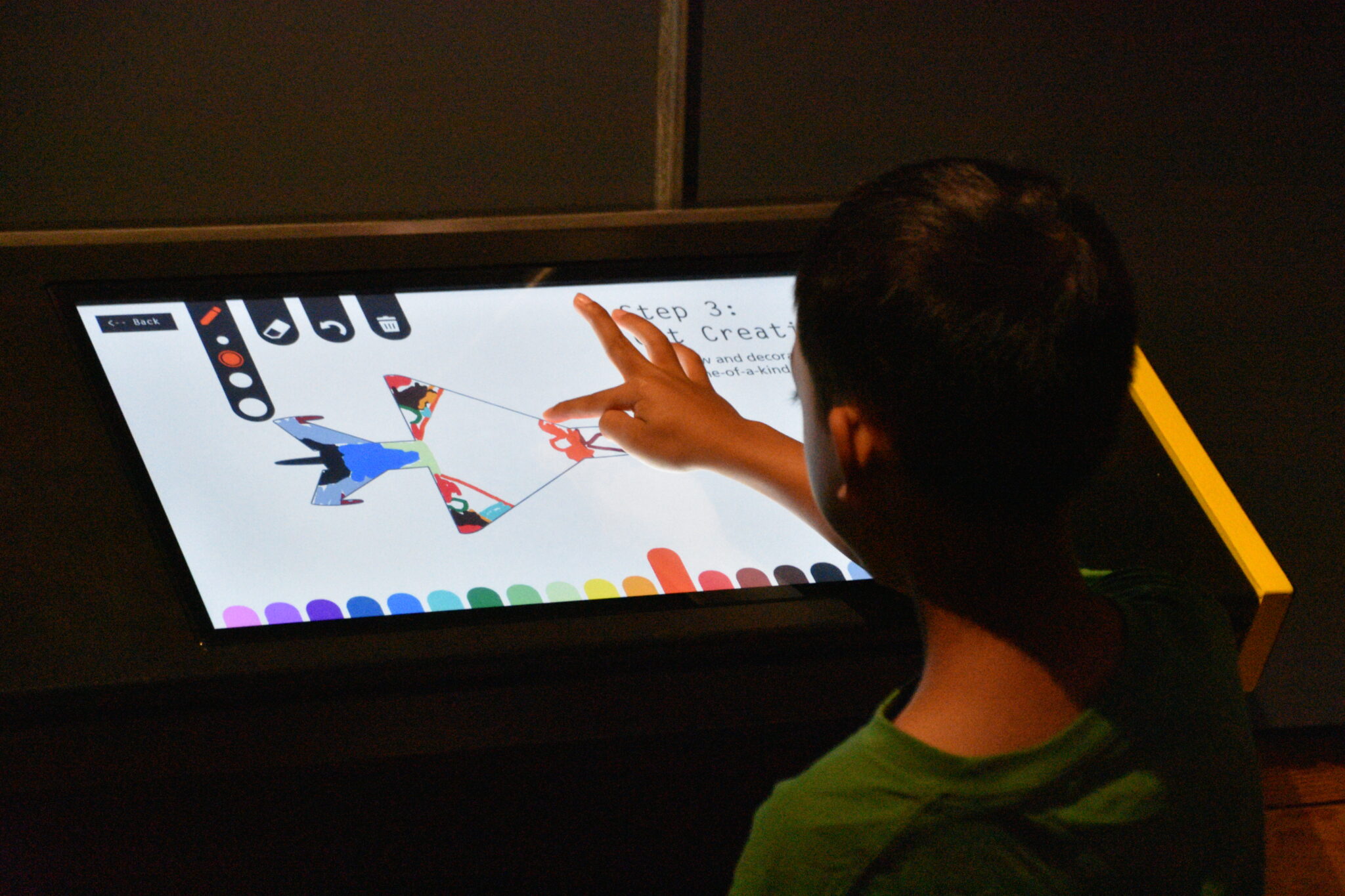 Young visitor engaging with digital art display at Museum of Flight