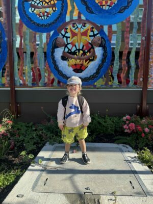 Child smiling outside preschool on the first day of school.