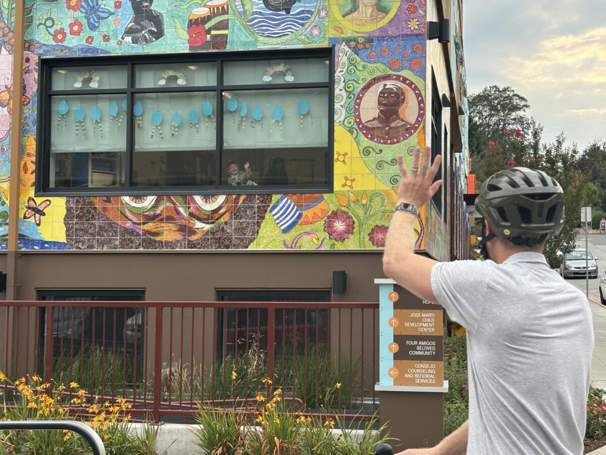 Dad waves goodbye to his preschooler through the classroom window during drop-off.