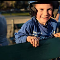 Young child smiling in a baseball uniform before a game.