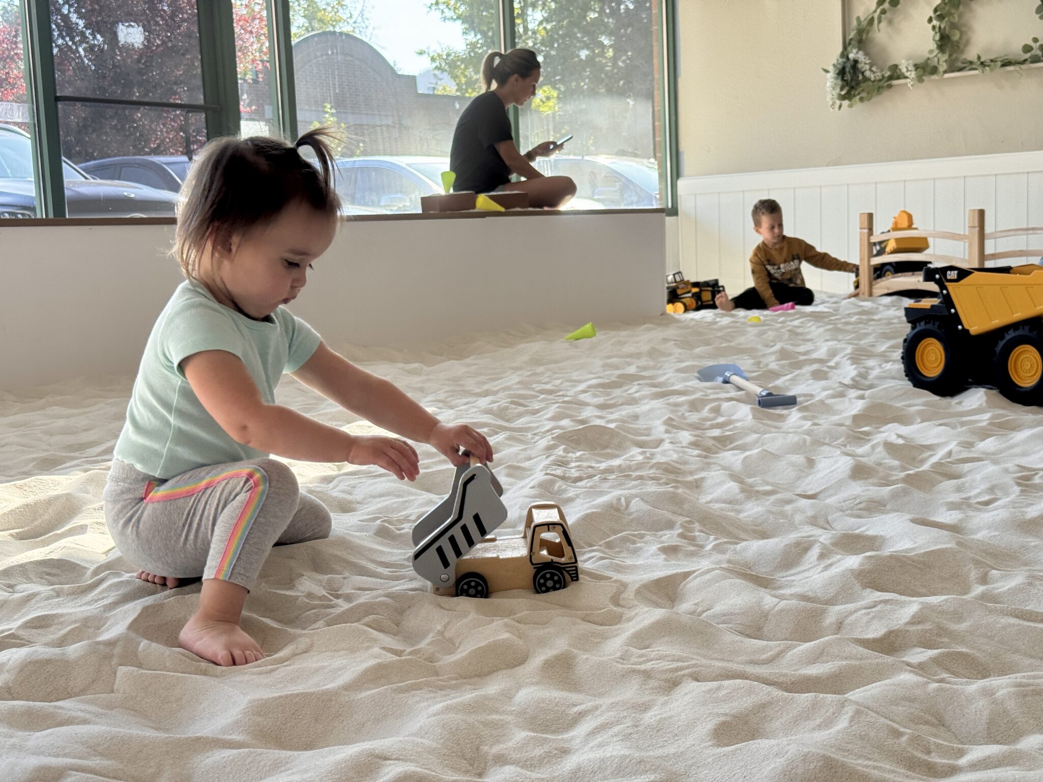 Toddler playing with a toy truck in the indoor sandbox at SandGarden in Issaquah