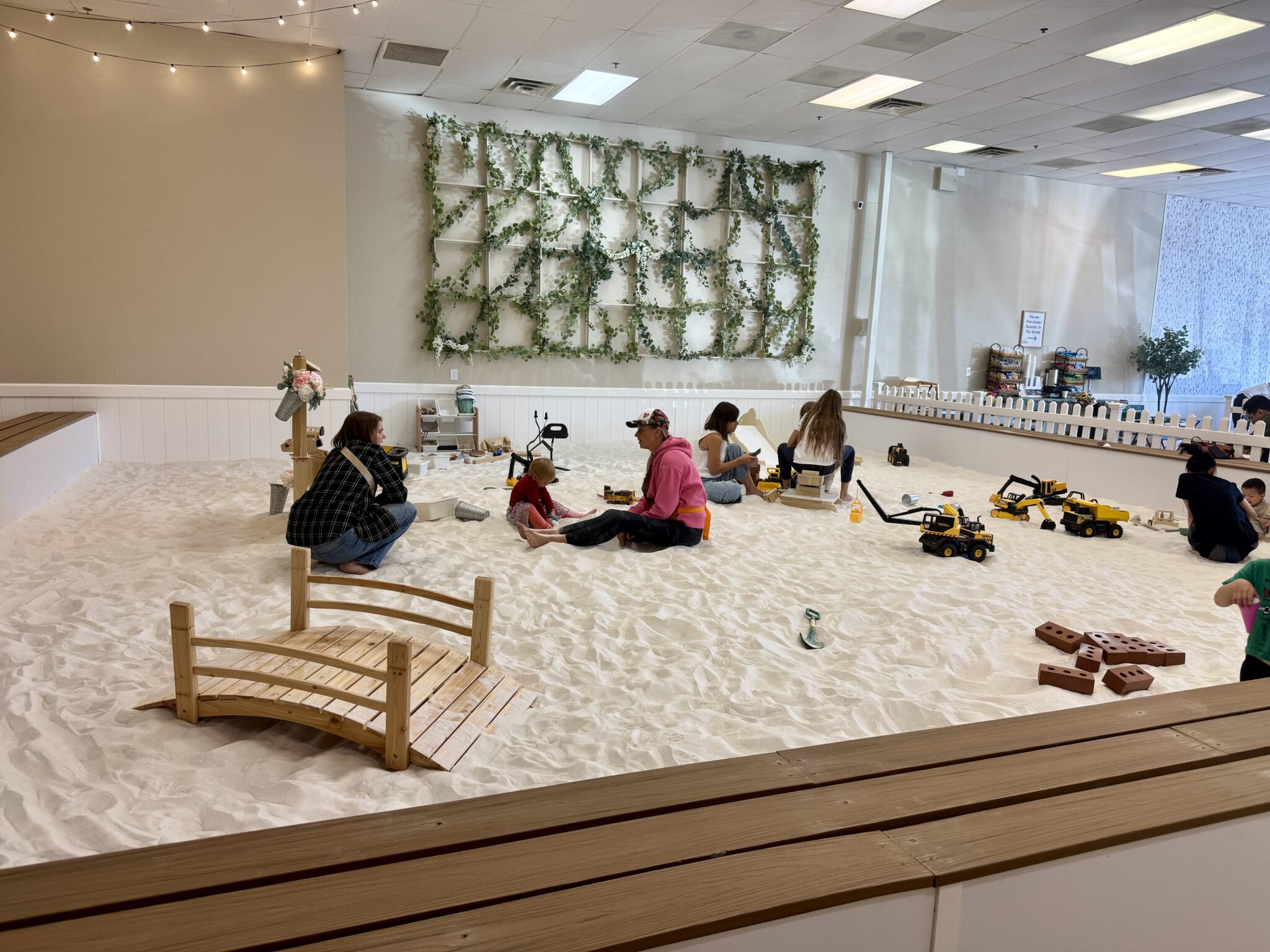 Wide view of SandGarden’s large indoor sandbox with kids and parents playing together