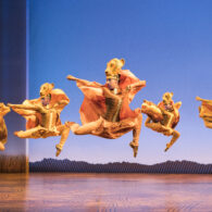 Actors in elaborate costumes perform “The Lion King” on stage.