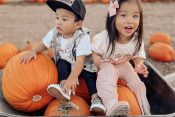 Two kids sitting on pumpkins in a wheelbarrow at Maris Farms in Buckley, Washington