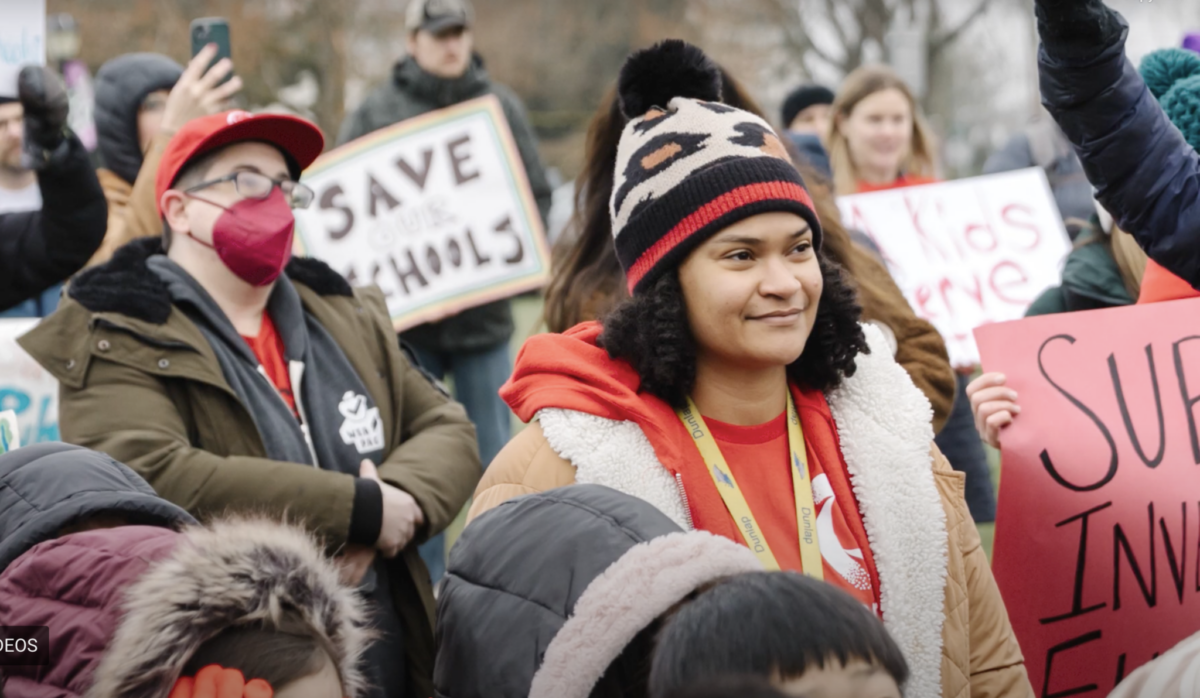 Parents, teachers and community members gather at a South Seattle Schools Fundraising Alliance event, holding signs in support of saving and investing in local schools.