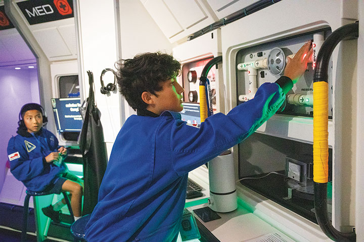 A young learner troubleshoots an alarm sounding during a simulated space mission in the Museum's Challenger Learning Center.