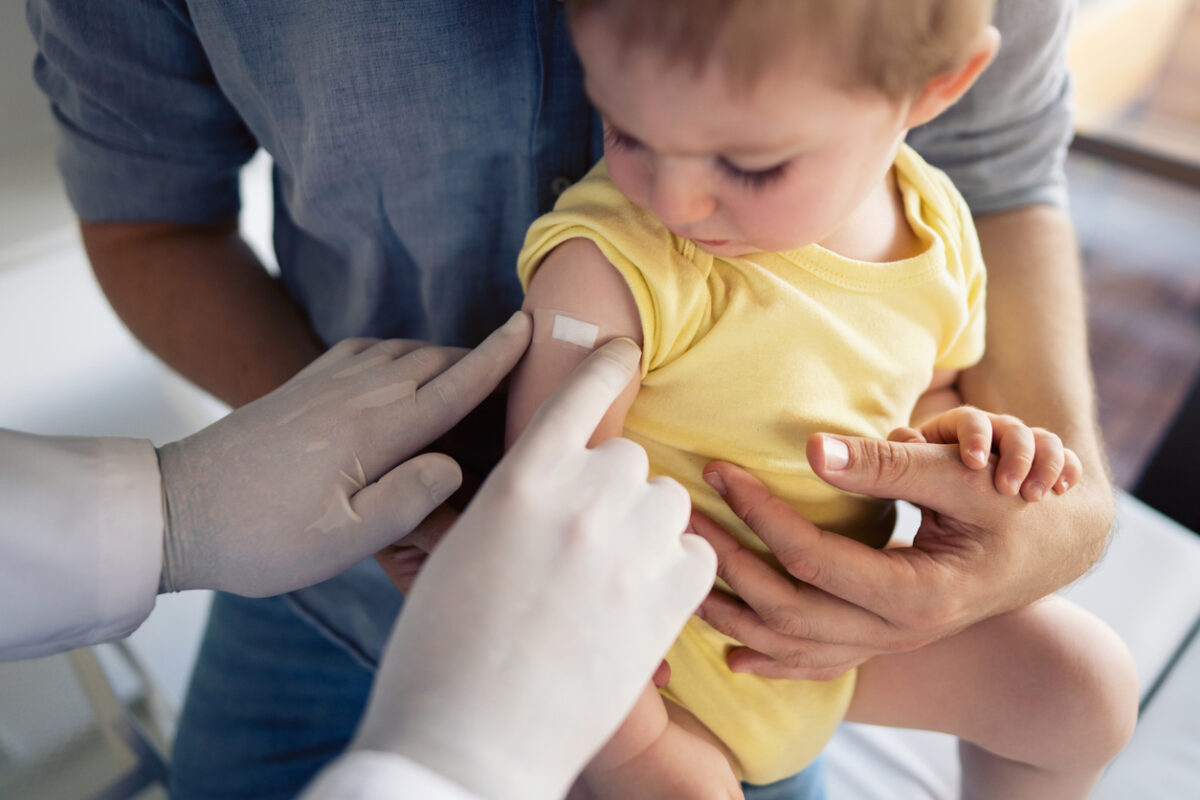 Pediatrician placing a bandage on a baby’s arm after vaccination.