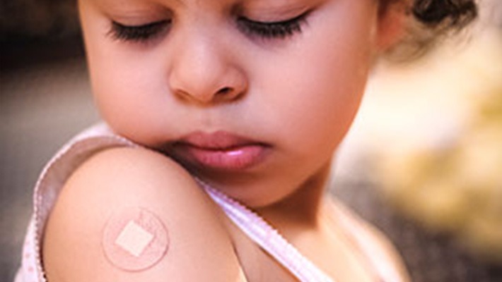 Child looks at bandaid on arm where RSV vaccine was administered at a Seattle pediatric clinic, part of efforts to protect babies and reduce winter hospitalizations.