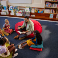 Adult leading a story time at a Seattle library, seated on the floor with young children gathered around and listening
