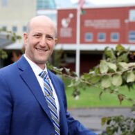 Headshot of Ben Shuldiner, smiling and wearing a blue suit jacket and shirt.