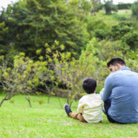 dad latin man in jean shirt enjoys his beautiful garden playing with little son in yellow shirt and beautiful sunny day